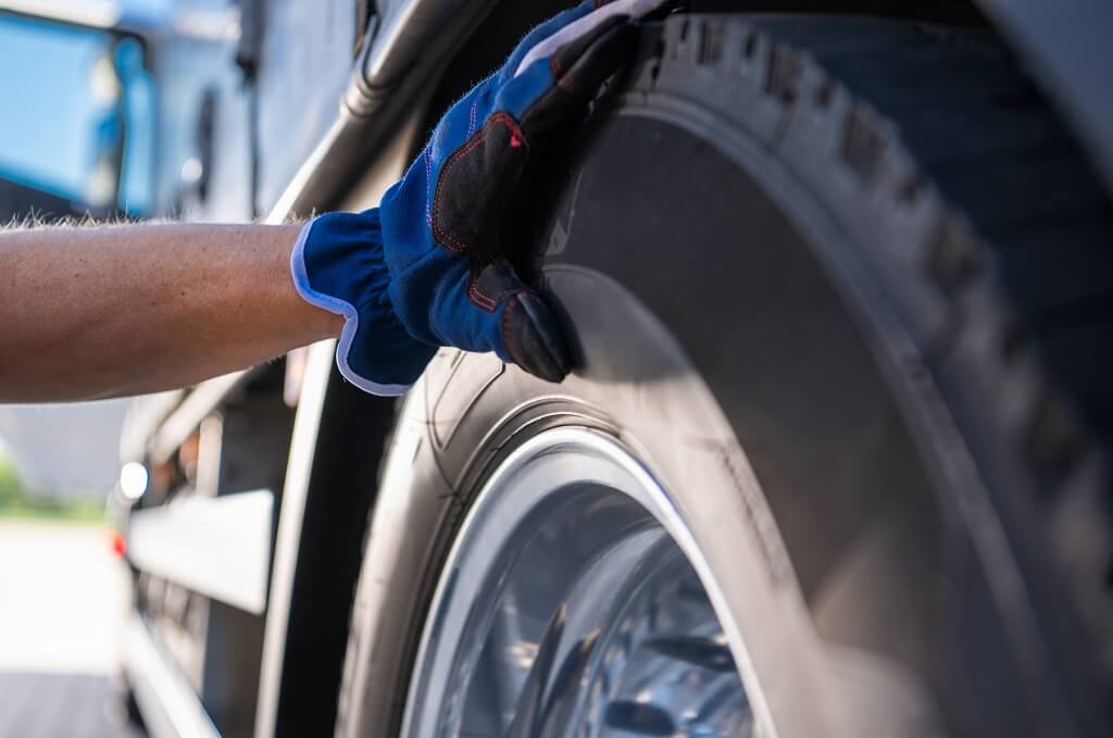 Ruka sa rukavicom proverava stanje i površinu gume na vozilu